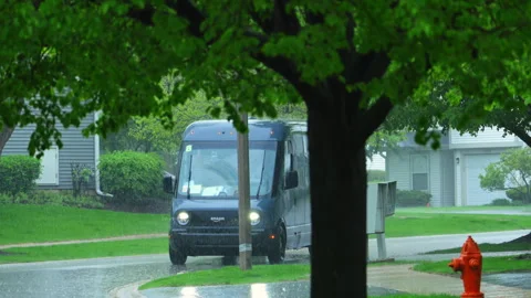 Rivian electric delivery Amazon van driving through rain in suburban Stock Footage 335968592
