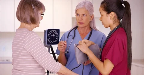 RN training nursing student to check patient blood pressure in clinic Видео 70584592