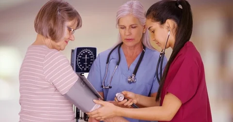 RN training nursing student to take senior patient blood pressure in hospital Video stock 70584084