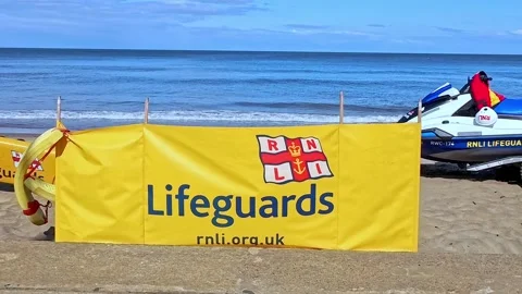 RNLI flag and jet ski on the beach. Push in shot Video stock 313564692