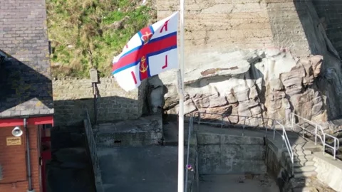 RNLI Flag flying at Cullercoats Stockbeeldmateriaal 253340574