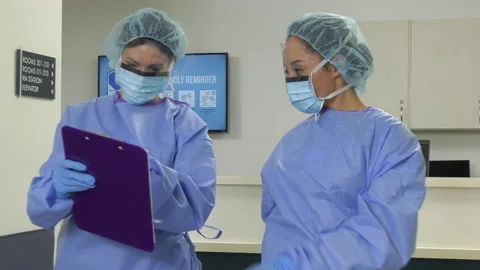 RNs in Full PPE Take Chart Walk Hall Stock Footage 137538408