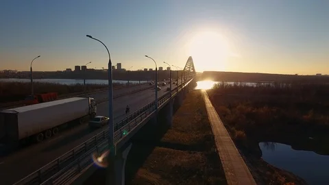 The road across the bridge at sunset, on which cars and motorcyclist are moving. Stock Footage 104646504