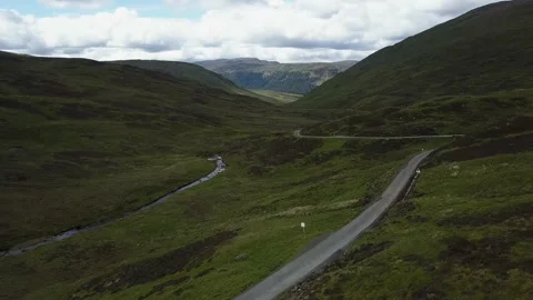 Road along stream through mountain pass landscape in United Kingdom Video stock 155464253