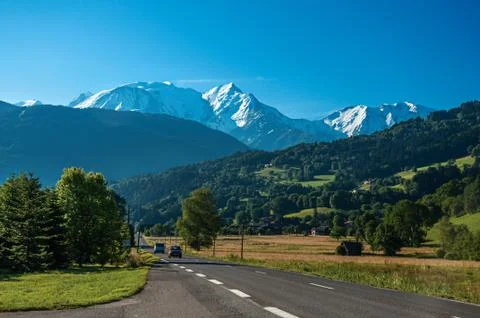 Road among fields, forests and alpine landscape near Saint-Gervais-Les-Bains. Stock Photos