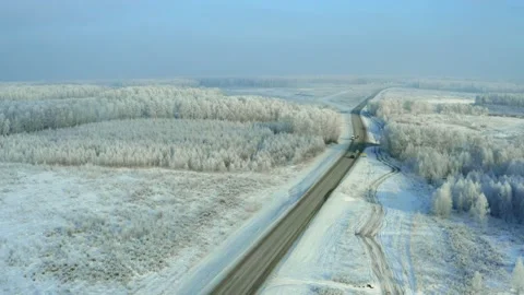 The road among snow fields and forests.  Drone view. Video stock 144661699