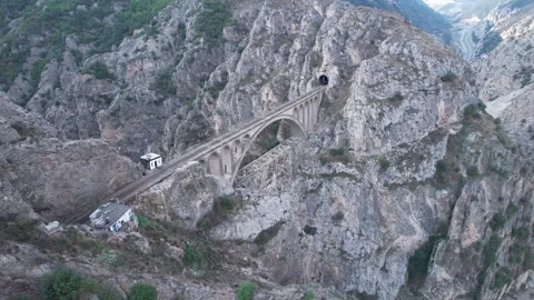 Road and bridge navigate rocky canyon terrain with steep walls under overcast Stock Footage 342704101