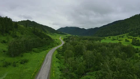 Road and car against the backdrop of a green mountain landscape in summer Stock Footage 254436014