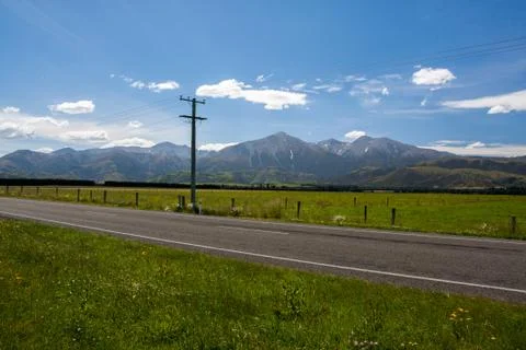 Road and fields under mountains Stock Photos