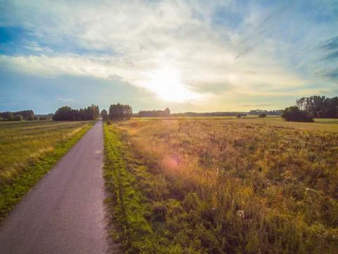 Road between fields, sunset, beautiful sky Stock Photos
