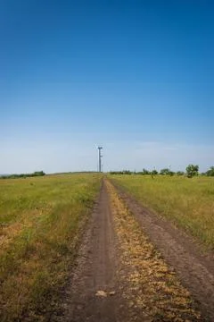 Road between green fields and wind turbines on blue sky background Stock Photos