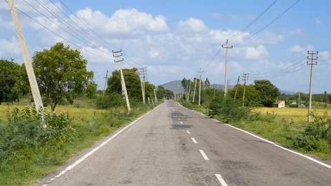 Road between green trees with light blue sky in rural India 動画素材 111303842