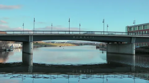 Road bridge over urban river with modern office block on river bank Stock Footage 1060904