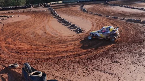 Off-road Buggy Drifts Through Red Dirt With Tire Barriers. - aerial shot Stock Footage 327452093