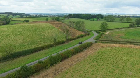 Off road buggy driving along narrow countryside road between agricultural fields Stock Footage 345501166
