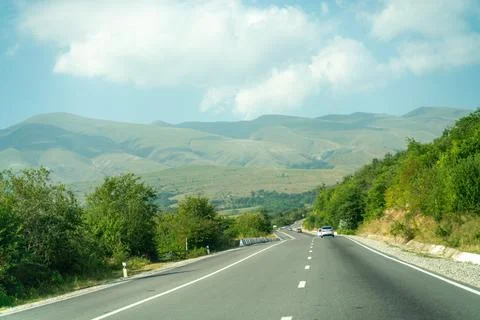A road with a car driving down it and mountains in the background Stock Photos