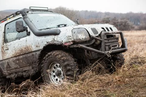 Off road car overcomning difficult pit on bad dirty road. Stock Photos