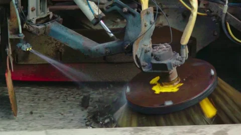 Road cleaning machine spraying water while rotating brush sweeps pavement during Stock Footage 344104234