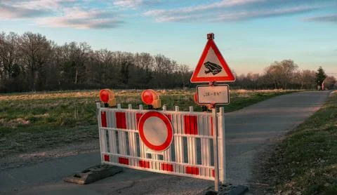 Road closure sign blocking access with warning of frogs in the evening Stock Photos