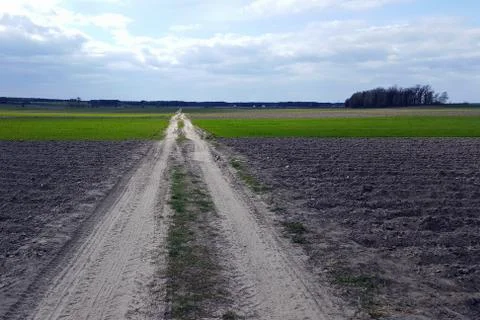 Road to the clouds, passes through a plowed field Stock Photos