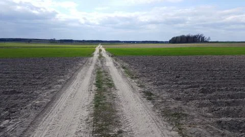 Road to the clouds, passes through a plowed field Stock Photos