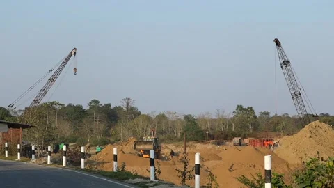 Road construction activity with cranes along rural highway Stock Footage 328340663