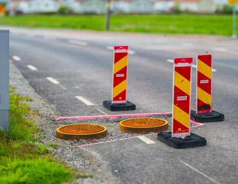 Road construction area with traffic warning signs and manholes. Stock Photos