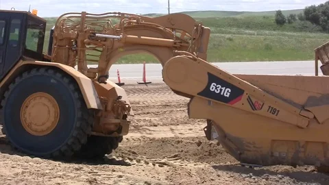 Road construction -B big earthmover turns near camera then away with dozer Stock Footage 104829691