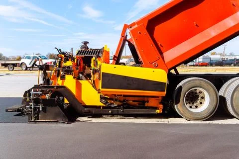 Road construction crew uses machine to lay asphalt in city Stock Photos