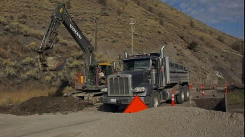 Road construction - excavator fills dump truck with debris, 4k Stock Footage 253437053
