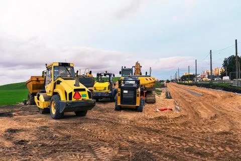 Road construction scene with a road roller, excavator, mini dump truck, and.. Stock Photos