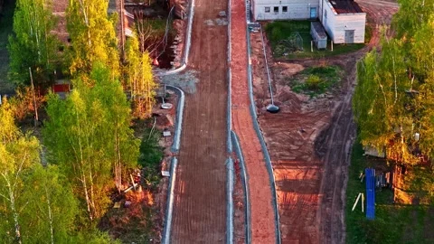 Road construction with sidewalk and bicycle path in a park at sunset in aerial Stock Footage 337514946