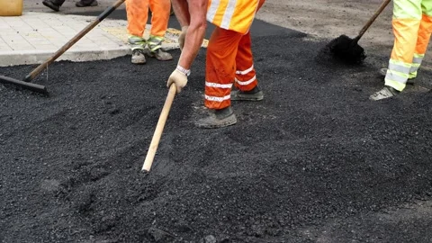Road construction team uses shovels to distribute new asphalt. Vídeo Stock 224739743