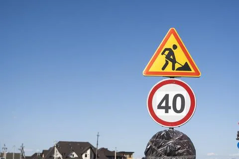 Road construction warning sign displaying a worker with a shovel and a 40 km per Stock Photos