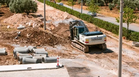 Road construction work. Excavator digging a trench and lays a sewer-pipe drain Stock Footage 50691028