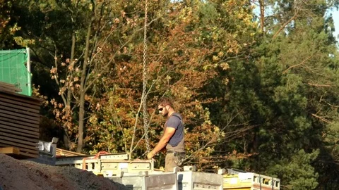 Road construction worker fixing chains of a construction crane to steel object Stock Footage 81473031