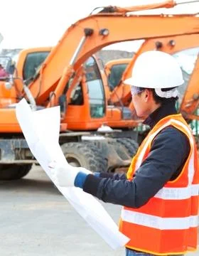 Road construction worker in front of excavator Foto stock