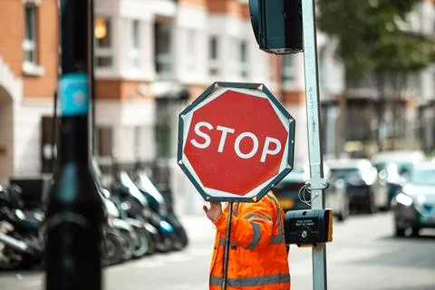 Road Construction Worker Holding a Stop Sign to Control Traffic Flow and En.. Stock Photos