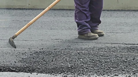 Road construction worker leveling asphalt using rake on the new road Stock Footage 51329415