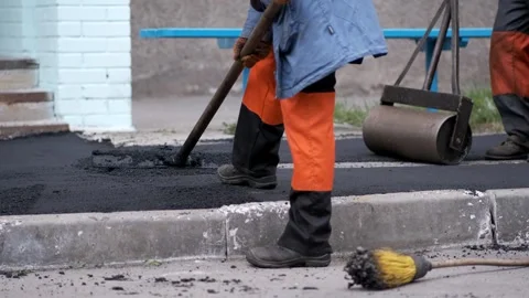 Road construction workers leveling fresh hot asphalt with a rake tool on a .. Stock-Footage 339802024