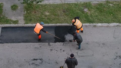 Road construction workers repairing asphalt pavement near manhole cover Stock Footage 339802336
