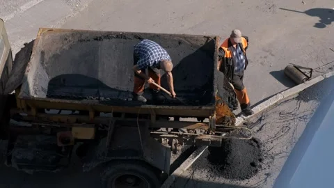 Road construction workers shoveling hot asphalt from truck bed during road .. Video stock 339801808