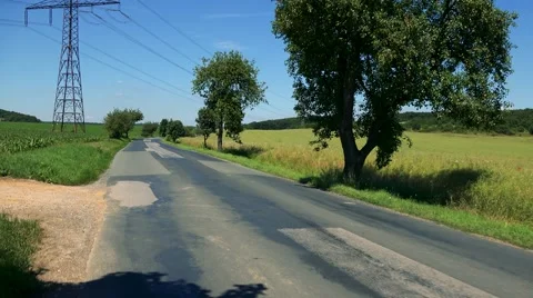 Road in the countryside between fields with trees - sunny day Stock Footage 67755344