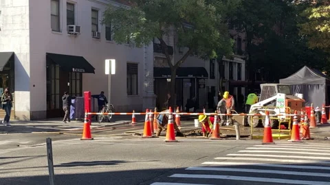 Road crews do major roadwork on a street in New York City while pedestrians wait Stock Footage 142841564