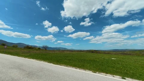 Road curves gently through green fields. Balkan, Eastern Europe, POV Video stock 333587026