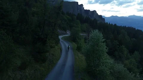 Road Cyclist Descending Through Trees Toward Gravel Road Stock Footage 344584624
