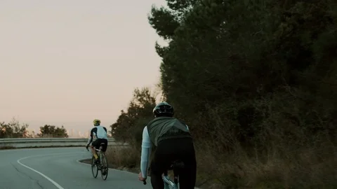 Road cyclists riding on sunset mountain road Stock Footage 107874964