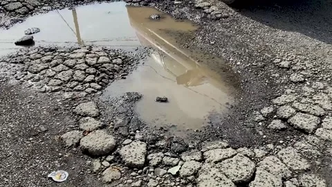Road destroyed after winter. Puddles in the pits in the road Video stock 160032101