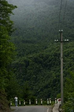 Road down, power line pole and mountain view, cloudy Stock Photos