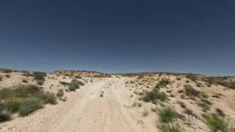 Off-road driving through rugged terrain with dirt path and clear blue sky Stock Footage 341976094